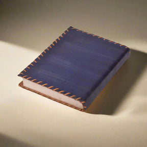 Blue leather notebook with brown stitching on a white background