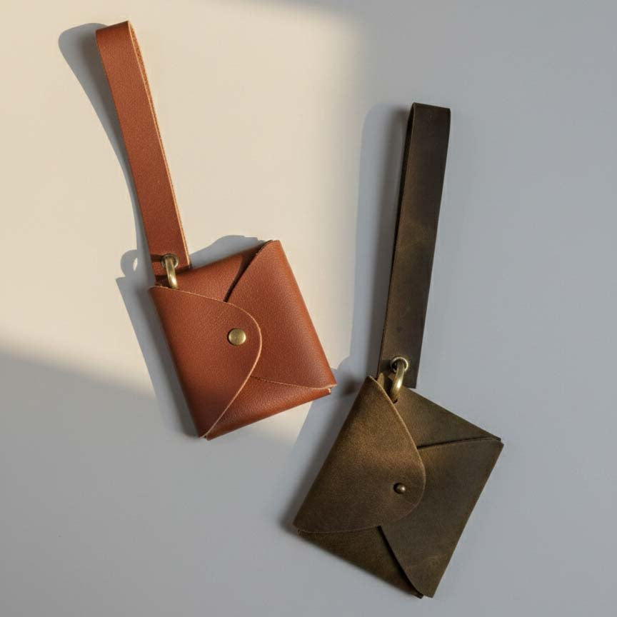Leather AirPod pouches with brass spring-gate keyrings side by side