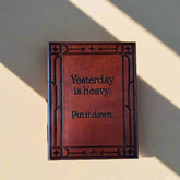 Brown leather notebook with text on a beige background