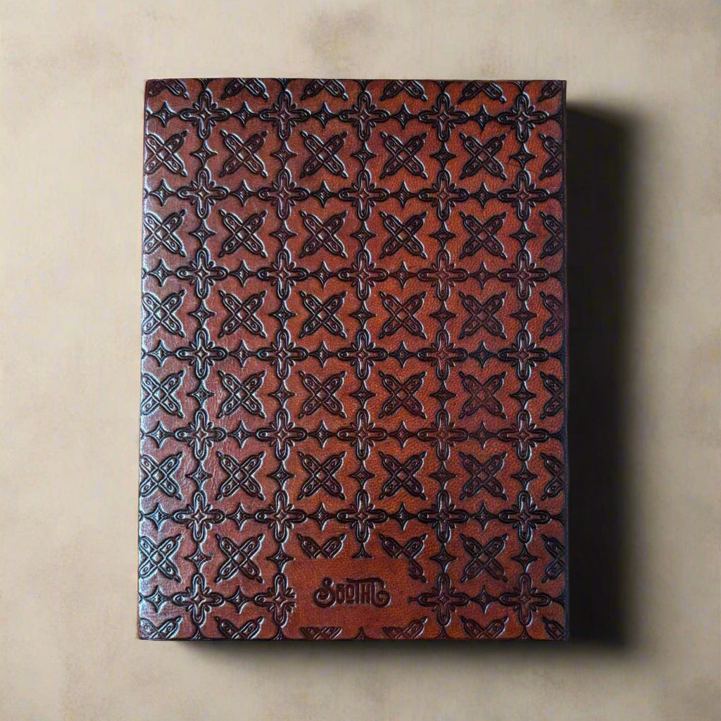 Brown leather notebook with embossed pattern on a beige background
