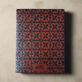 Brown leather notebook with embossed pattern on a beige background
