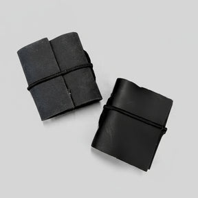 Two black leather-bound notebooks on a peach-colored background
