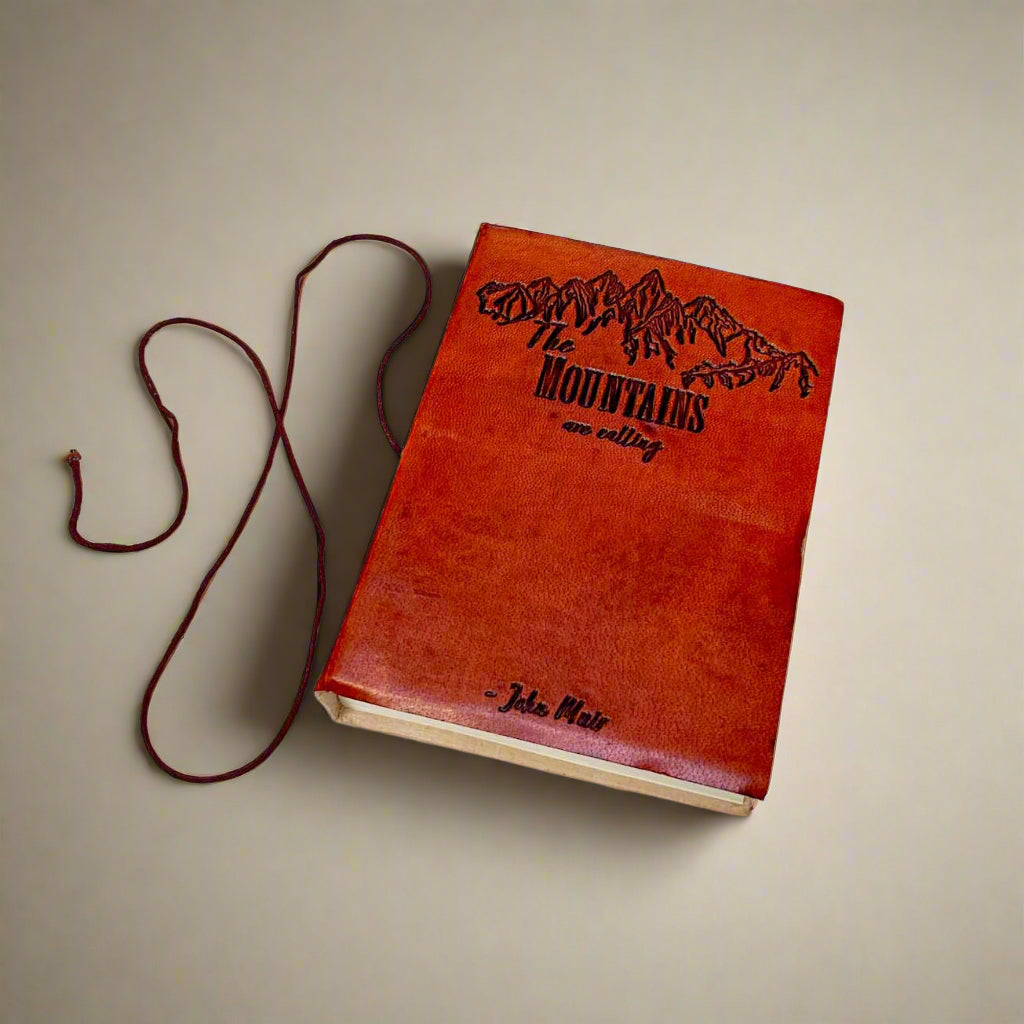 Two journals with leather covers, one in tan and one in brown, both with embossed text and artwork.