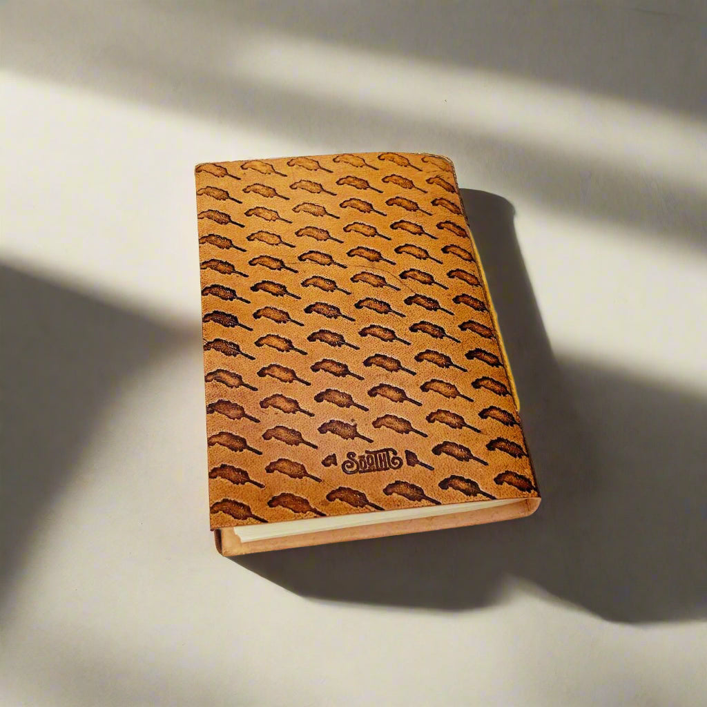 Back cover of a leather notebook with a debossed quill pattern.
