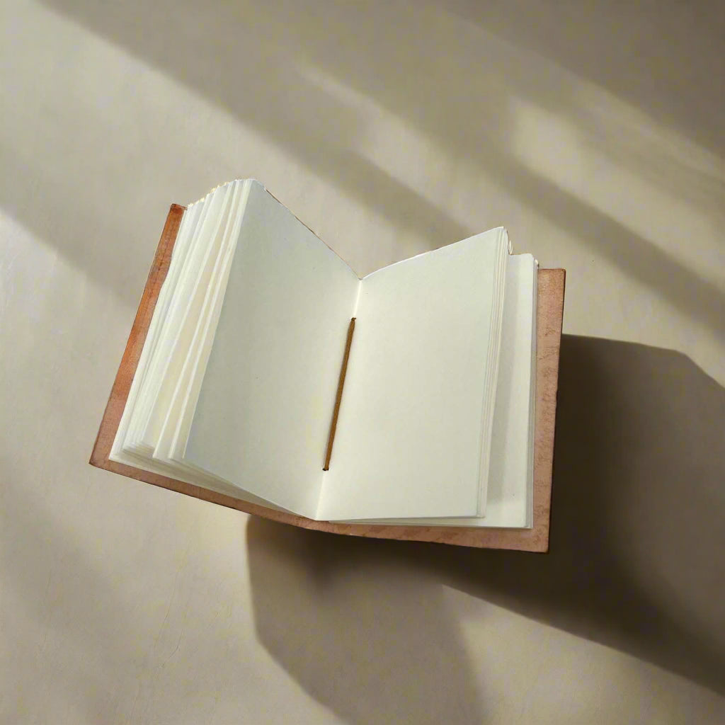 Leather notebook open to unlined handmade tree-free cotton-waste paper pages.
