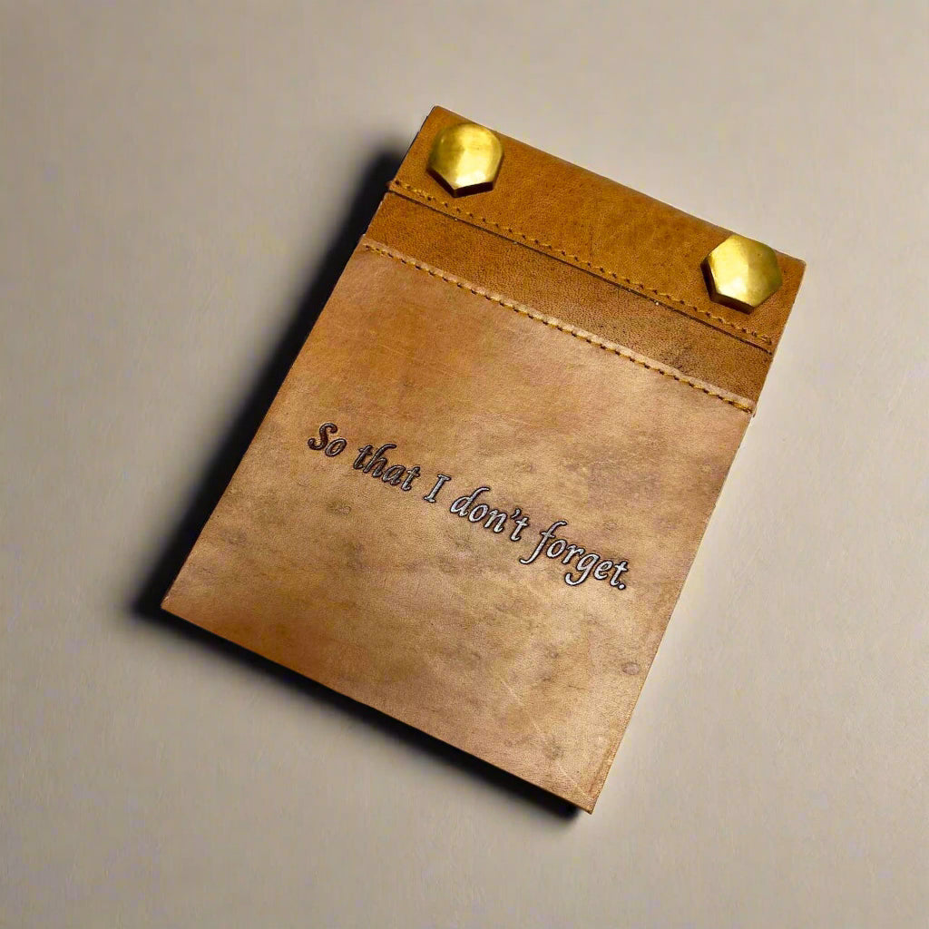 Blonde tan leather notepad with screw-post binding on desk