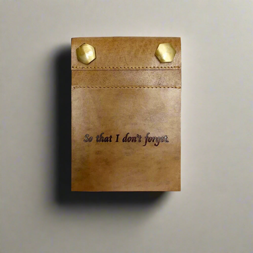 Refillable leather notepad with pen on wooden desk