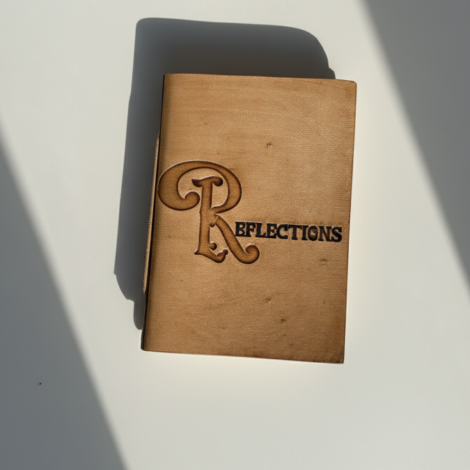 Brown leather notebook with 'Reflections' embossed on a white surface