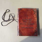 Brown leather-bound book with text and a lanyard on a light background