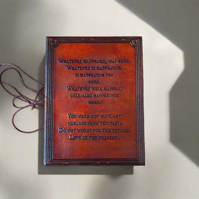Brown leather-bound book with engraved text on a beige background