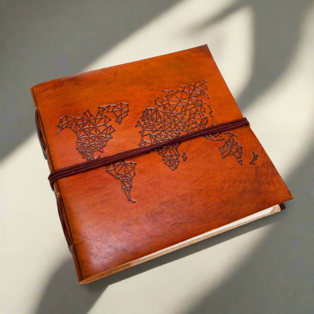 World Map 7x7 leather journal held in hand for scale